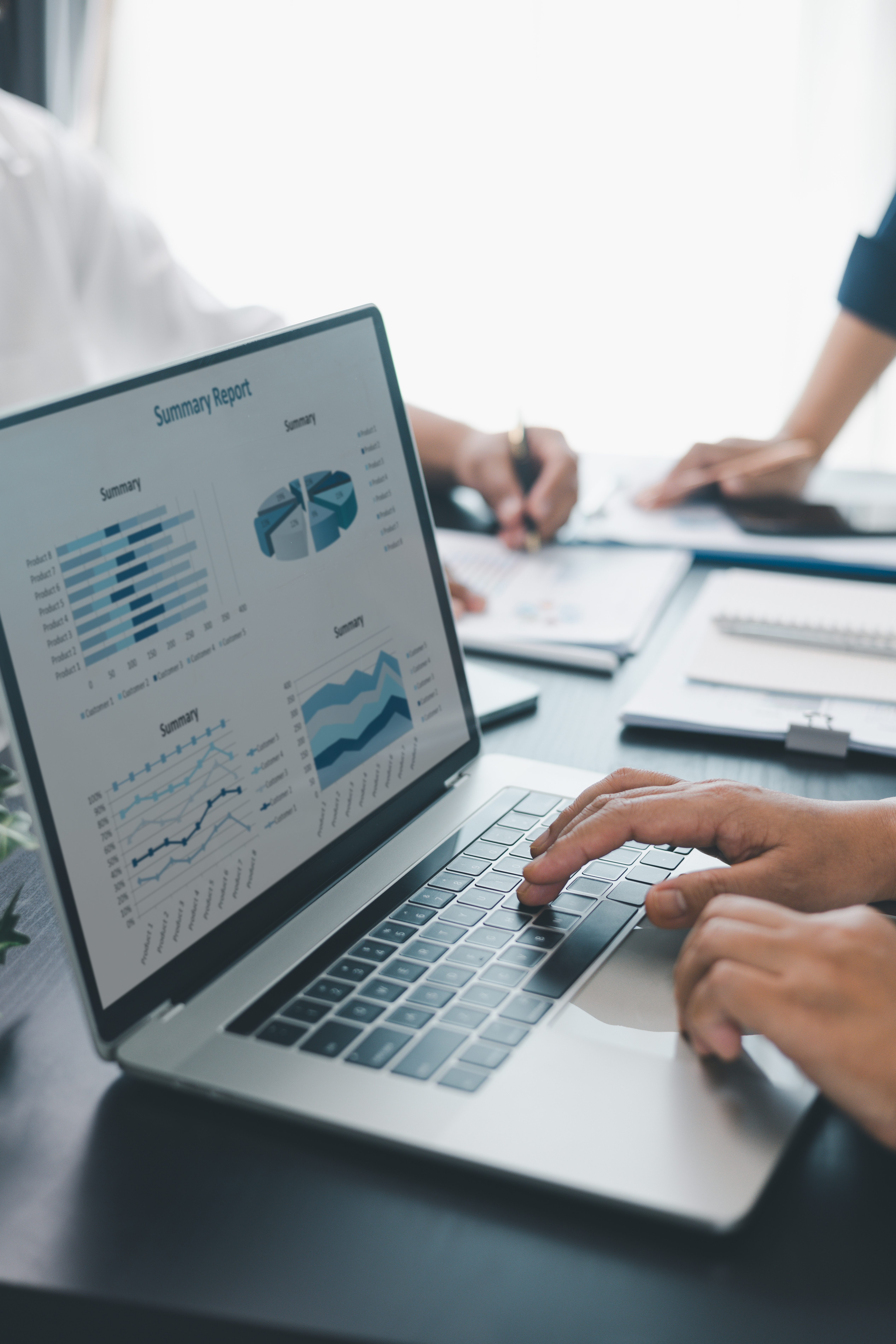 Business data analysis concept with colleagues reviewing financial report on laptop, pointing at chart with growth graph, teamwork discussing statistics, planning strategy and corporate success.